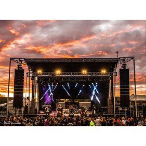 Stageline SL320 mobile stage at an outdoor concert at sunset with line array speakers and lighting rig